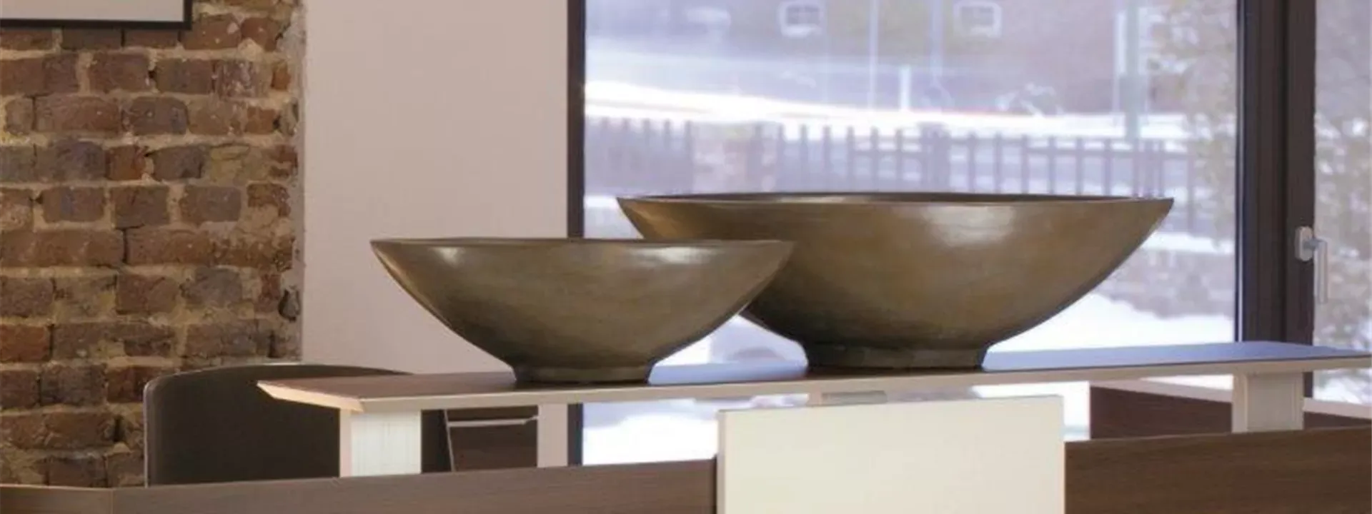 Zwei flache Pflanzschalen in Verdigris Bronze auf einem Empfangstresen